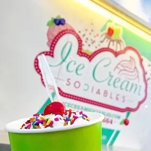 a cup of ice cream with sprinkles and a cherry