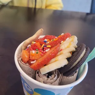 an ice cream sundae with a banana, chocolate cookie, and sprinkles