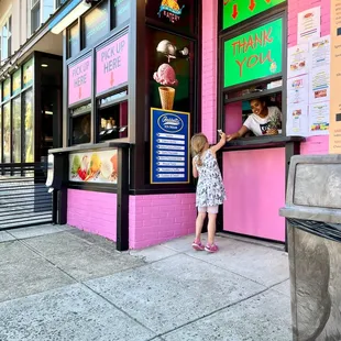 a little girl standing in front of an ice cream shop