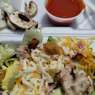 a salad with cheese, mushrooms, and lettuce