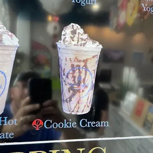 a woman taking a picture of a cup of ice cream