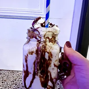 a hand holding a chocolate milkshake