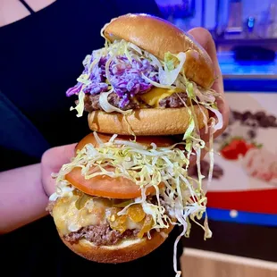 a person holding a hamburger with lettuce, tomato, and cheese