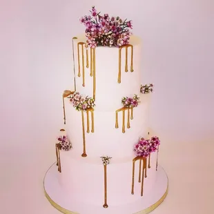 a three tiered cake with drips and flowers