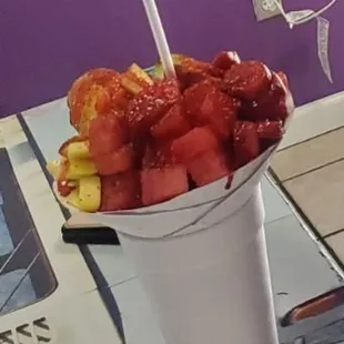 a cup of fruit with a straw in it