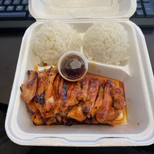 a take out container with rice and chicken