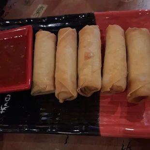 a plate of fried spring rolls with dipping sauce