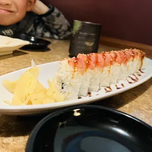 a child sitting at a table with a plate of sushi