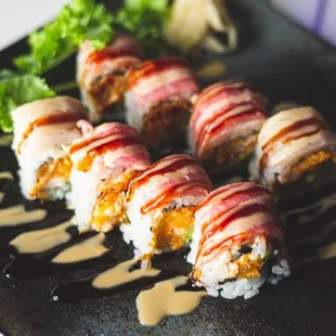 a plate of sushi with sauce and lettuce