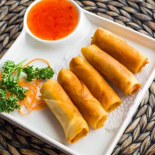 a plate of spring rolls with dipping sauce