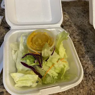 a container of lettuce and a bowl of mustard