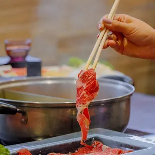 a person using chopsticks to stir the meat