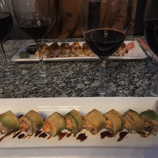a plate of sushi rolls and a glass of red wine