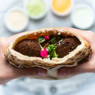 a person holding a pita sandwich