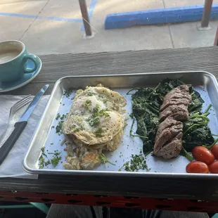 Over medium steak and eggs with spinach and hash browns.