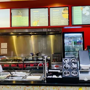 a restaurant counter with menus on the wall