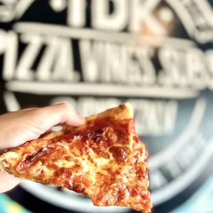 a hand holding a slice of pizza