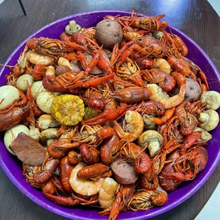 a large purple bowl filled with crawfish, potatoes,