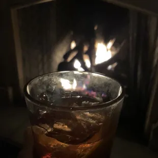 a close up of a drink in front of a fireplace