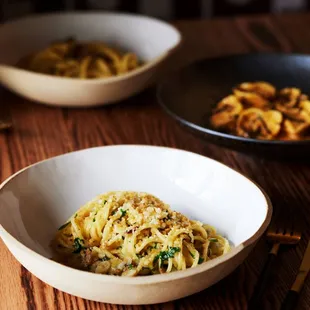 two bowls of pasta on a wooden table