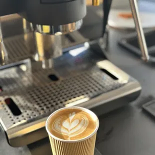 a cup of cappuccino in front of a coffee machine