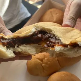 a person holding a sandwich with a bite taken out of it