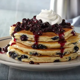 a stack of pancakes with blueberries and whipped cream