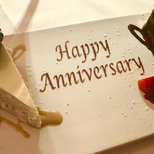 a piece of cake on a plate with the words happy anniversary written on it