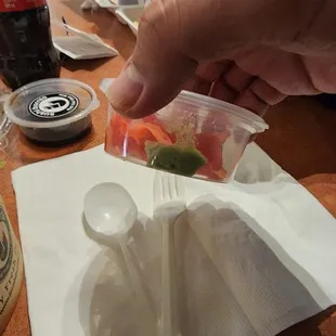 Ginger with a tiny thing of wasabi. Soy sauce in similar packaging to the left on the table.