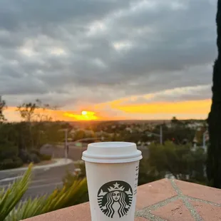 a starbucks cup sitting on a brick ledge