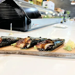 three sushi rolls on a cutting board