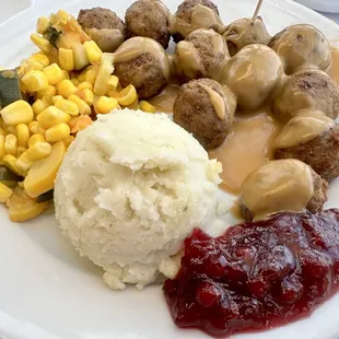 a plate of meatballs, mashed potatoes, corn and cranberry sauce
