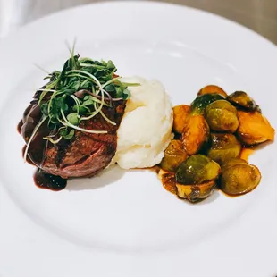 a steak with mashed potatoes and brussels sprouts
