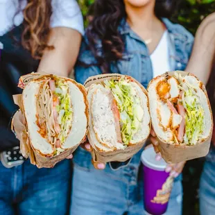 three people holding sandwiches