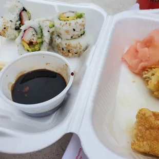 a tray of sushi and a bowl of sauce