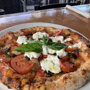 Our new pizza - olives, tomatoes, burrata cheee and topped off with basil!.  Simply a delicious vegetarian pizza