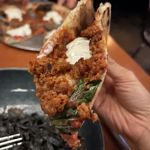 a hand holding a piece of pizza