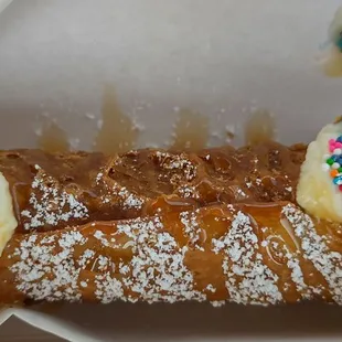 Traditional cannoli with mascarpone, rainbow sprinkles, and caramel drizzle