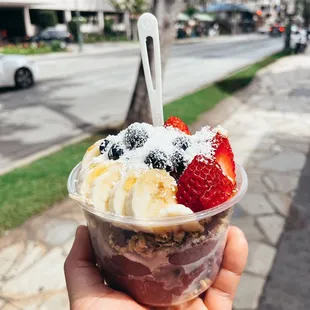 a hand holding a bowl of fruit