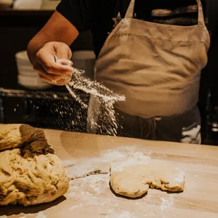 a man sprinkling flour on a doughnut