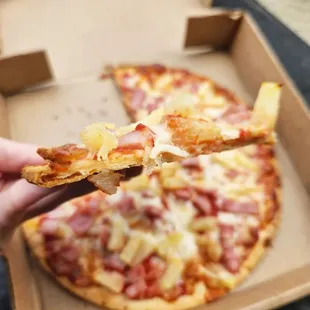 a hand holding a slice of pizza