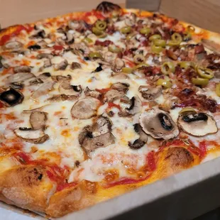 Fluffy, chewy pizza with double mushrooms, bacon and green olive on half.