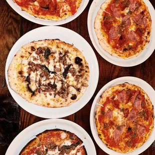 a variety of pizzas on plates