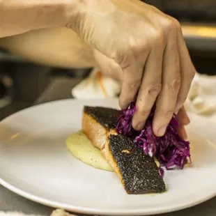 a person placing a piece of food on a plate