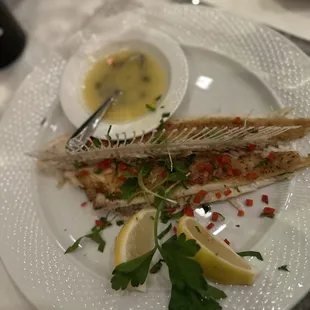 a plate of fish with lemon wedges