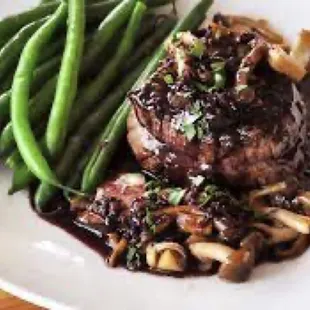 a plate of meat with mushrooms and green beans