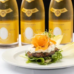 a plate of food and three bottles of wine