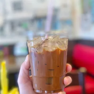 a hand holding a glass of iced coffee