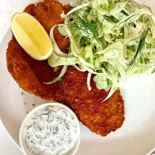 a plate of food with a lemon wedge and salad