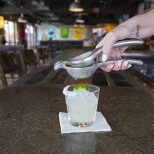 a person squeezing a drink into a glass